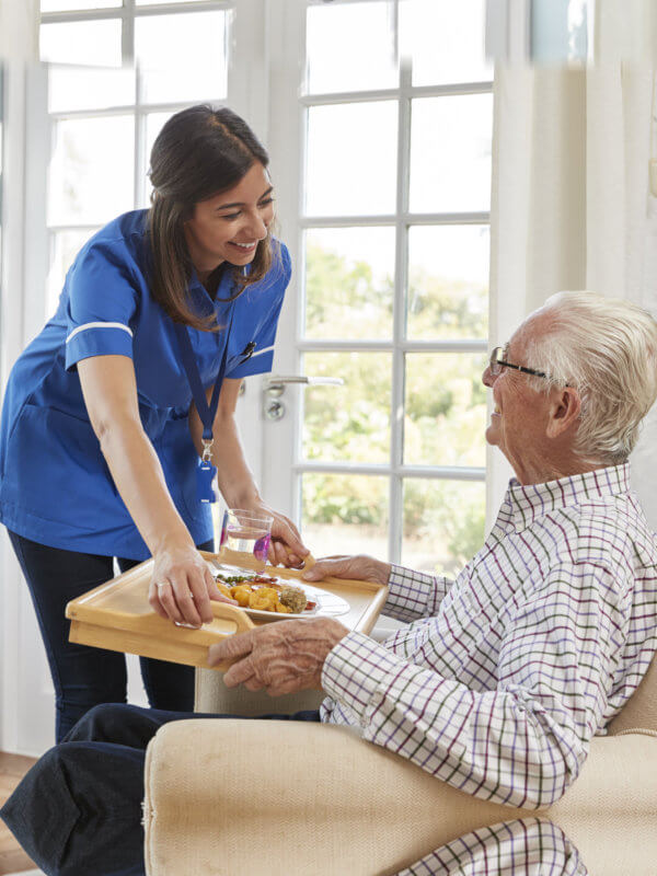 nurse hadning food to elderly man