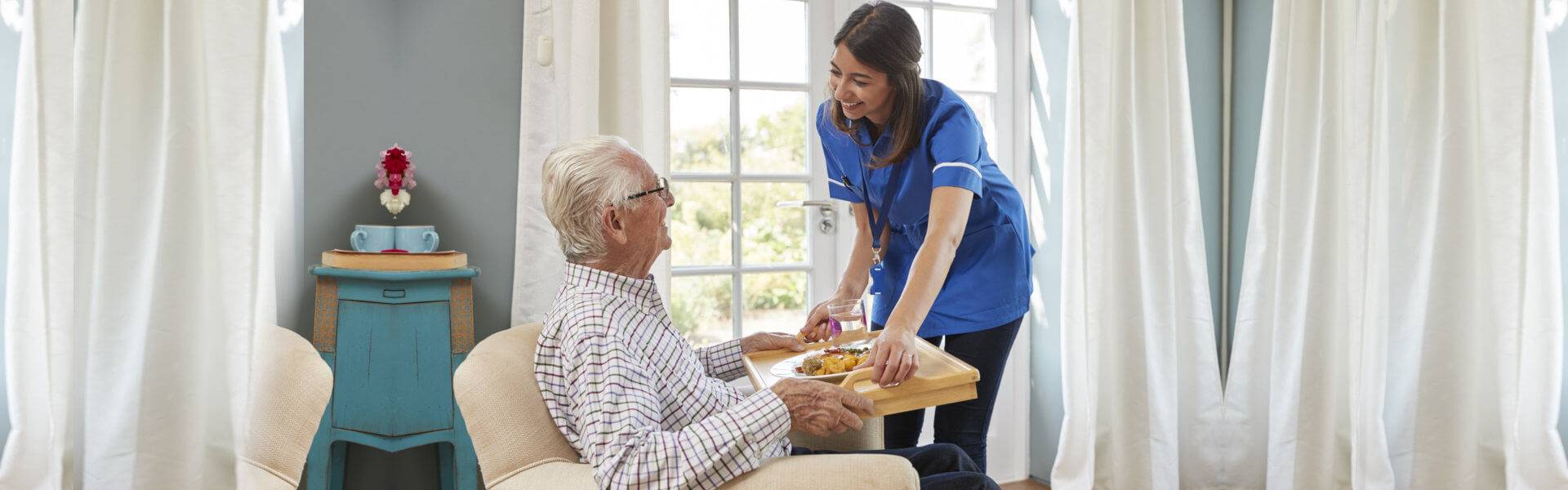 nurse hadning food to elderly man