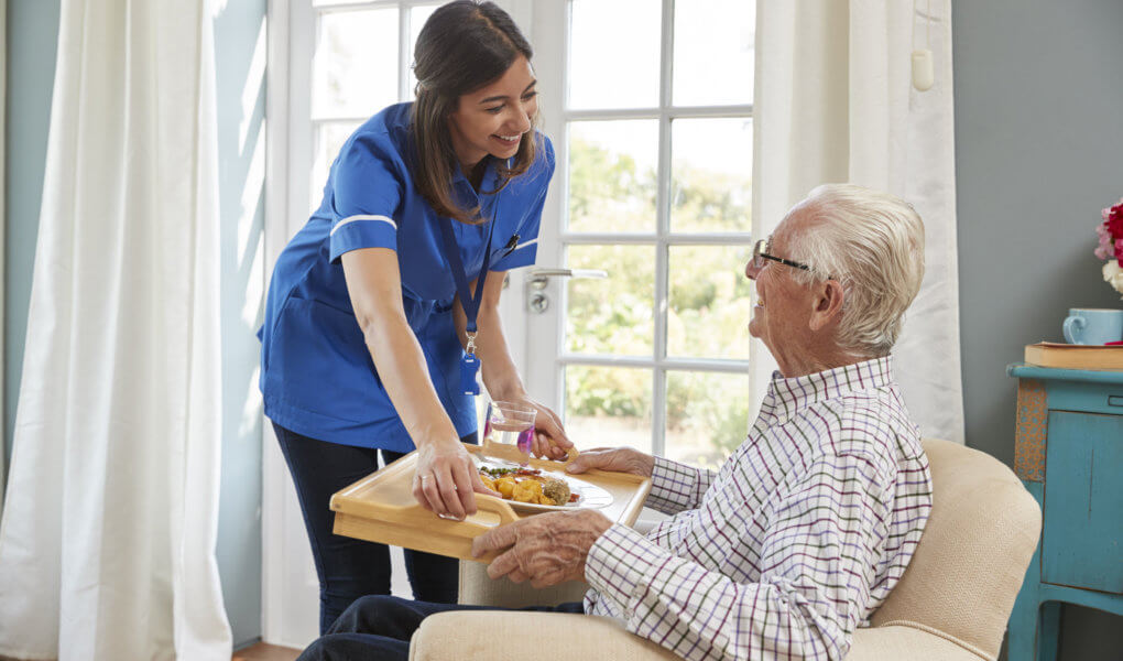 nurse hadning food to elderly man