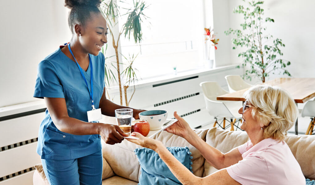 nurse serving to elderly woman